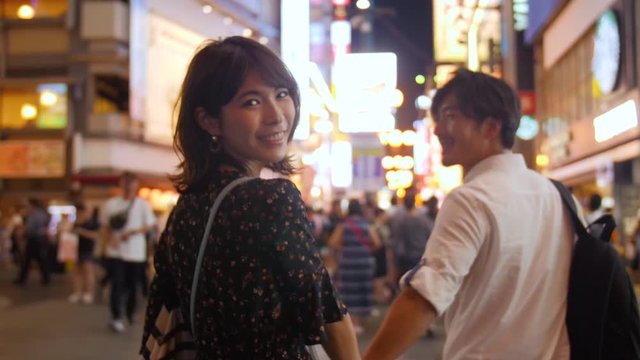 Beautiful women looking back at camera slow motion walking holding hands with boyfriend trip