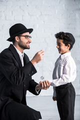 side view of smiling jewish father giving star of david necklace to son