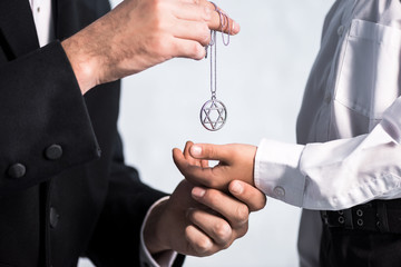 cropped view of jewish father giving star of david necklace to son