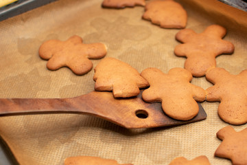 Christmas hot cookies are collected with a small wooden spatula from a baking sheet. Warm light, selective focus