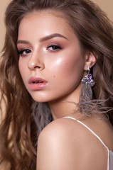 Photo of a beautiful girl with professional delicate brown makeup and natural lips. Fashion ostrich feather earrings