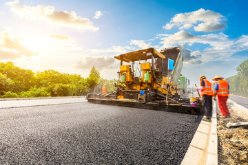 Construction site is laying new asphalt road pavement,road construction workers and road construction machinery scene. © ABCDstock