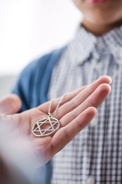 cropped view of jewish father holding star of david necklace on son