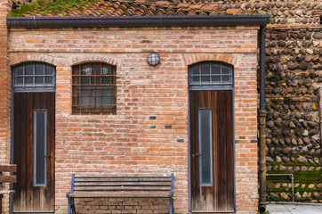 The old house made from the red bricks with wooden door and bench, old red brick wall - Image