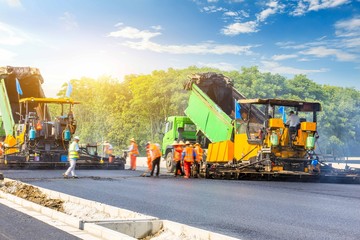 Construction site is laying new asphalt road pavement,road construction workers and road construction machinery scene.