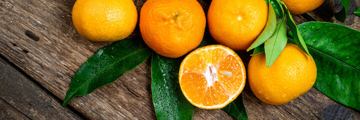 Tangerine, mandarines, clementine, orange fruits with green leaves on wooden table. Fresh...
