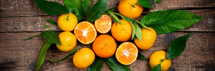 Tangerine, mandarines, clementine, citrus fruits with leaves on wooden table. Fresh tangerines citrus fruits background. Long web format