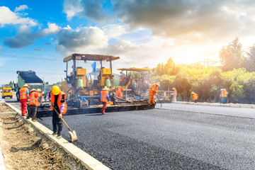 Construction site is laying new asphalt road pavement,road construction workers and road construction machinery scene.