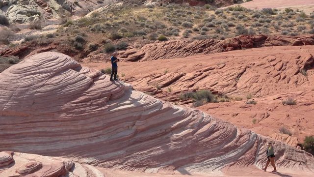 Valley Of Fire, United States - December 04, 2019: 4K. Young photographer boy on top of the popular Fire Wave Trail. Taking a break from walking. Young Caucasian in Valley of Fire State Park.