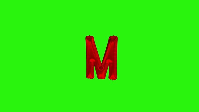 Red letter M. Red foil helium balloon alphabet floating on green screen