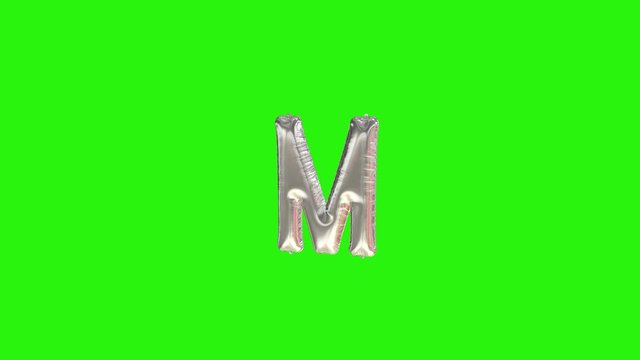 Silver letter M. Silver foil helium balloon alphabet floating on green screen