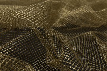 Beautiful close up of gold tulle fabric with textile texture background