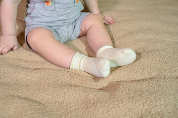 Little legs in the white socks of a small child. Baby on a large parent bed. Happy childhood.