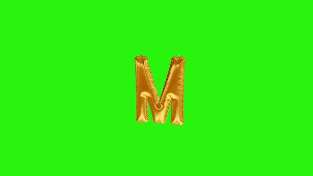Golden letter M. Gold foil helium balloon alphabet floating on green screen