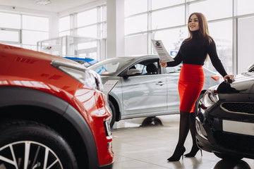 A stylish young girl is looking for a new car in a car store