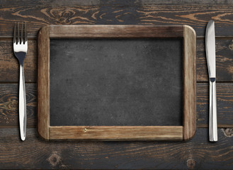 menu blackboard frame on old wooden dinning table with knife and fork