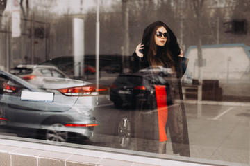 Fototapeta na wymiar A young woman is choosing a new car in car store