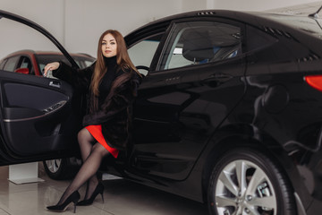 Obraz na płótnie Canvas A young woman is choosing a new car in car store