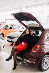 A young woman is choosing a new car in car store