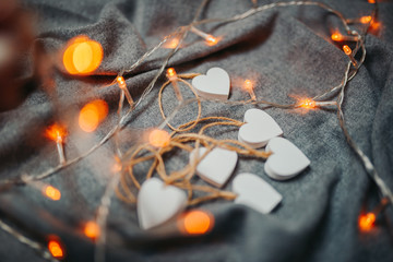 Saint Valentine's day card. White wooden hearts on the gray background. Hearts with garland light.