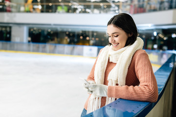 beautiful happy girl using smartphone on skating rink