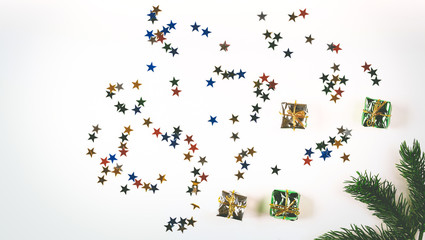 White christmas background. Decorative multi-colored stars. Christmas decorations. Spruce branch. Top view.