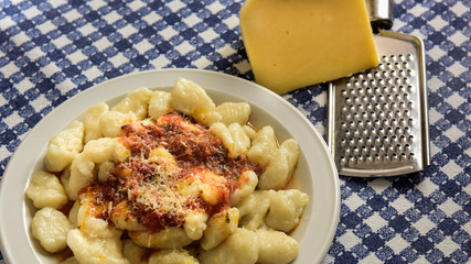 Plate of homemade gnocchi with grated cheese on the table