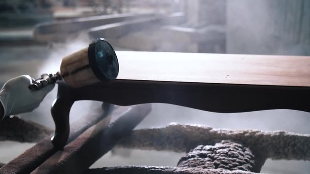 Close up Video Shot of Carpenter Working at his Workplace while covering Table with Lacquer. Brown piece of Luxury Furniture becoming more Beautiful. Man wearing mask and white gloves