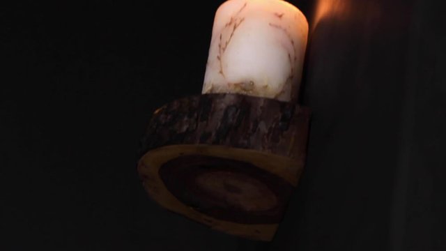 Candle light burning on a decor wood peice in the dark, handheld trippy shot 