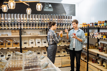choosing in grocery shop. Zero waste shopping - man buying healthy food in bulk products in dispensers and food available. Sustainable shopping at small local businesses.