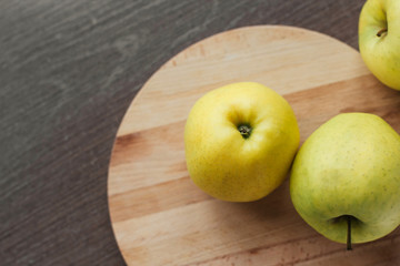  Ripe green apples on a round wooden cutting board on the table copy space. Harvest apples.