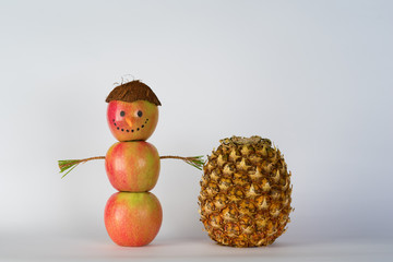 Concept of Sustainable, Zero waste, Summer Vegan Christmas. Creative snowman from apples, apple man in a hat from coconut and a pineapple standing on white background.