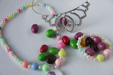 silver tiara next to children's multicolored beads and sweets in multi-colored glaze