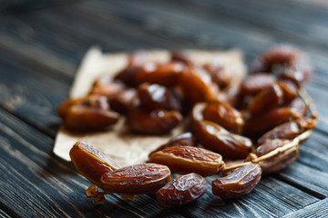 Sweet dessert dried date on an old dark wooden table. Low key, selective focus. Delicious ingredient for vegan dessert