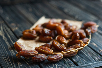 Sweet dessert dried date on an old dark wooden table. Low key, selective focus. Delicious ingredient for vegan dessert