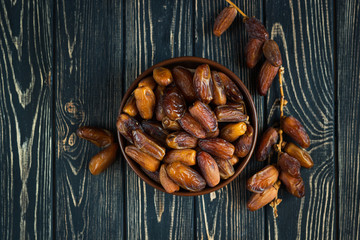 Sweet dessert dried date in brown ceramic bowl on an old dark wooden table. Low key, selective focus. Delicious ingredient for vegan dessert. Close up