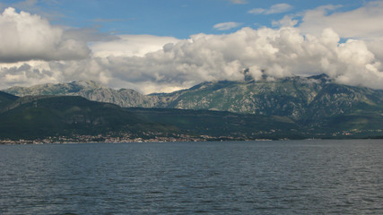 Fototapeta na wymiar panoramic view from the ship to Kotor bay and the surrounding mountains, blue sky with white clouds, Montenegro