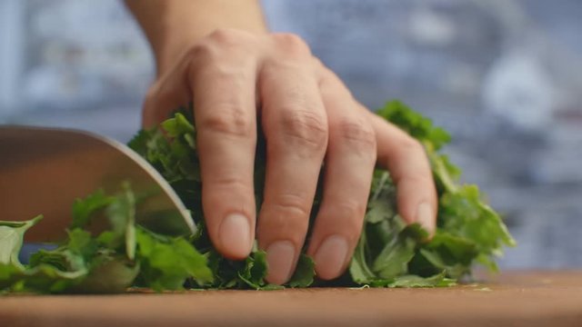 Close-up of cut parsley on a board in the kitchen with a knife.