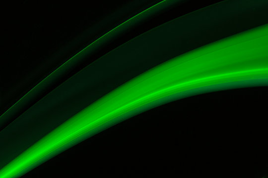 A close up macro photo of a diagonal wisp of green smoke on a black background that makes an abstract artistic retro background