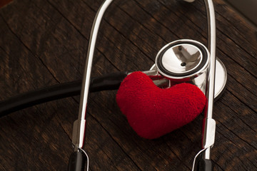 A doctor's stethoscope with red heart on wood background