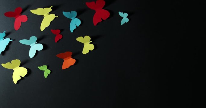 Stop motion motion of paper butterflies on a dark background.