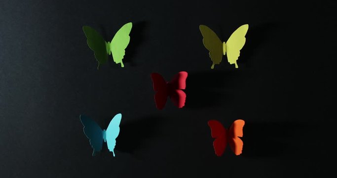 Stop motion motion of paper butterflies on a dark background.