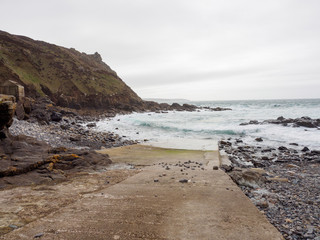 Wide angle view of a concrete boat ramp along the beach of Priest's Cove on a cloudy day. Cape Cornwall, United Kingdom. Nature and fishing. - 312219742