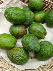 Green avocados in a basket at a market