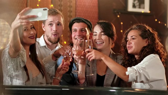 Young Cheerful Female Friends Taking Selfie In Pub Using Phone. Friends, men, women, leisure, friendship and technology concept - friends with smartphones drinking beer at bar or pub