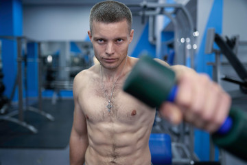 Fototapeta na wymiar Muscular guy with nude torso trains in gym