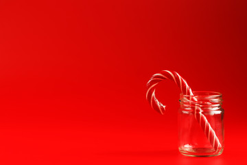 Lollipop Candy cane in a glass jar on a red background.