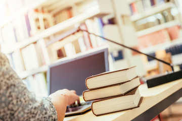Learning for exams: Blonde female student in the university library, pile of books