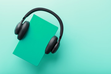 Headphones are worn on a book in a blue hardcover on a blue background, top view.