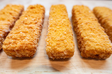 Fish fingers on a wooden chopping board.
